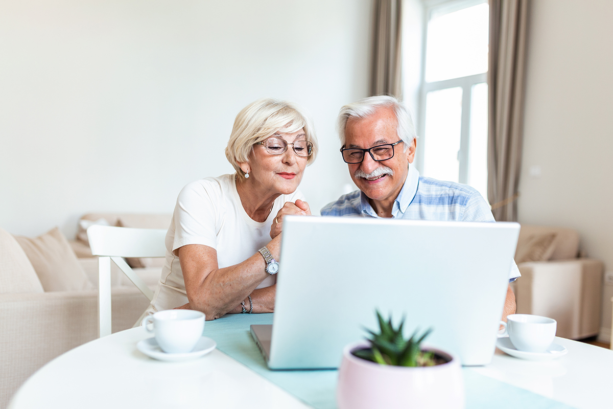 Happy old family couple talking with friends and family using laptop , surprised excited senior woman looking at computer waving and smiling. Seite Immobilie verkaufen